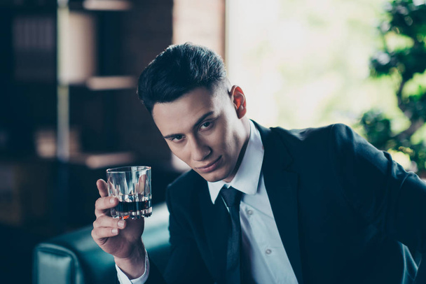 Close up photo handsome he him his pensive ponder hands arms whisky beverage enjoy pause break toasting wear formal-wear dress code shirt jacket tie suit costume sit chair indoors office place - Zdjęcie, obraz