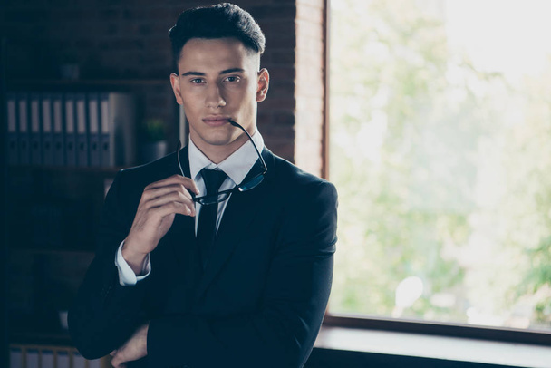 Close up photo perfect look handsome he him his thoughtful hand arm specs near mouth lips best boss attentive self-confident wear formal-wear shirt jacket tie suit costume indoors modern office place - Photo, image