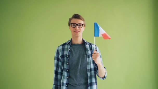 Slow motion of good-looking guy with French flag looking at camera and smiling - Materiał filmowy, wideo