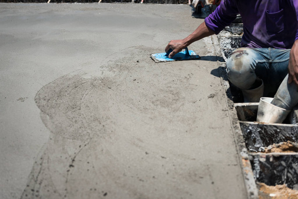 Plasterer beton cement werk. Mason nivelleren de vloer. Met behulp van een kunststof vierkante Troffel voor gladde of nivellering betonnen plaat vloer werk stap van de bouw. - Foto, afbeelding