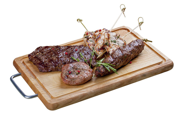 Set of grilled meat on a wooden Board. Chicken fillet, beef steak, pork medallion, lamb kebab. On a white background - Photo, Image