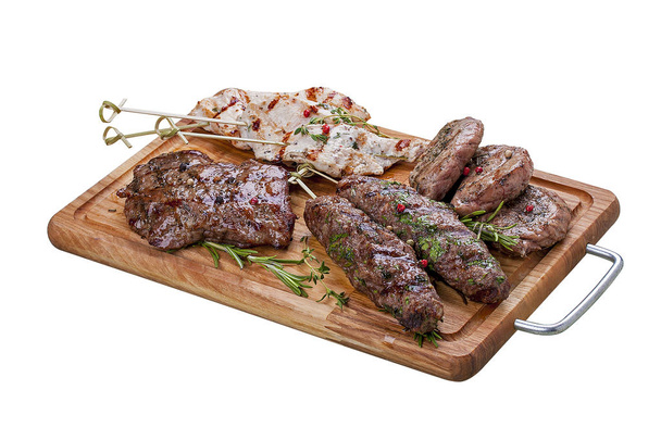 Conjunto de carne a la parrilla en una tabla de madera. Filete de pollo, filete de res, medallón de cerdo, kebab de cordero. Sobre un fondo blanco
 - Foto, Imagen