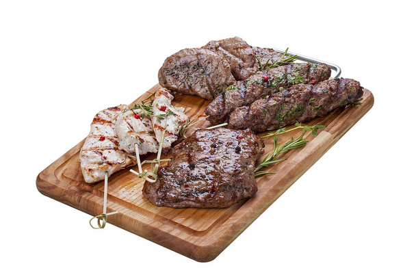 Set of grilled meat on a wooden Board. Chicken fillet, beef steak, pork medallion, lamb kebab. On a white background - Photo, Image