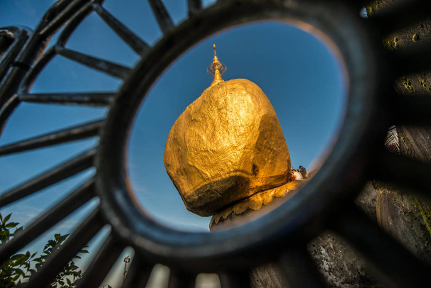 La pagoda de roca dorada (Kyaikhtiyo) un lugar popular icónico en el estado de Mon en Myanmar. Mira a través de la valla
. - Foto, imagen