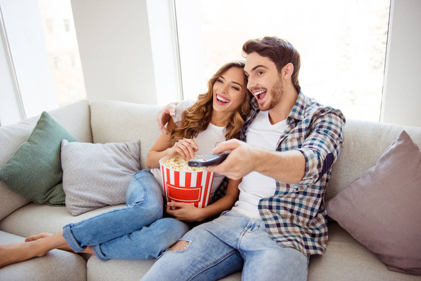 Portrait of his he her she two person nice attractive lovely charming cheerful guy lady spending time sitting on divan watching hilarious funny movie in light white style interior living room house - Photo, image