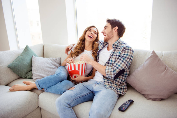 Portrait of his he her she nice attractive lovely charming cheerful cheery positive guy lady sitting on divan watching new hilarious funny film in light white style interior living room hotel house - Foto, immagini