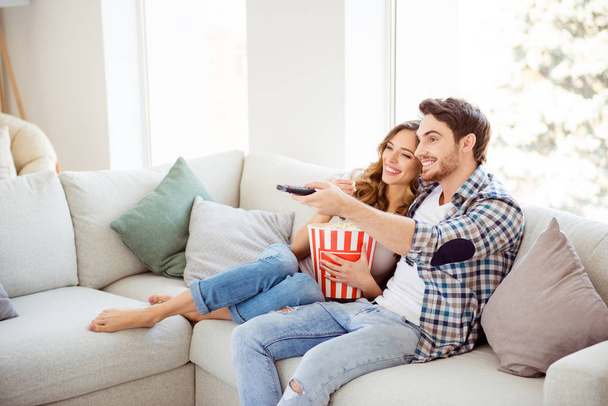 Profile side view of his he her she two person nice attractive charming cheerful guy lady sitting on divan watching new drama comedy in light white style interior living room hotel house indoors - Foto, Imagen