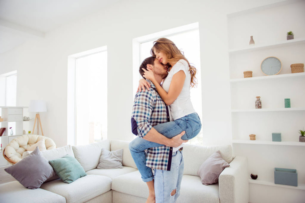 Profile side view portrait of nice attractive passionate guy kissing seducing keeping wavy-haired lady life lifestyle honeymoon in light white style interior living room hotel house - Fotografie, Obrázek