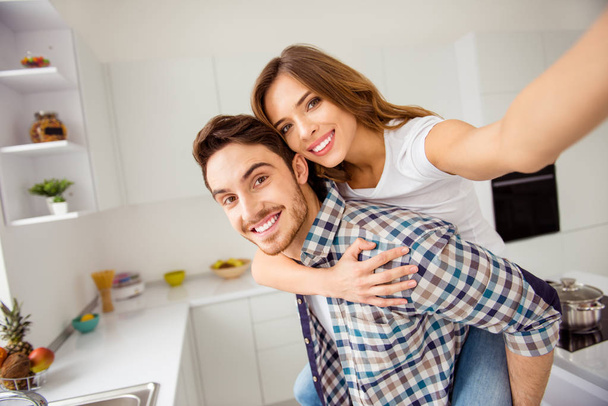 Close up side profile photo pair beautiful funky pair he him his macho she her lady just married honeymoon overjoyed piggy back pose make take selfies bonding apartments flat bright kitchen indoors - Fotografie, Obrázek