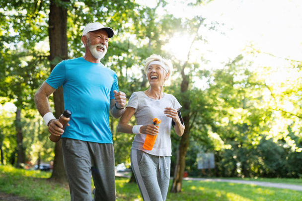 Senior couple jogging and running outdoors in nature - Zdjęcie, obraz