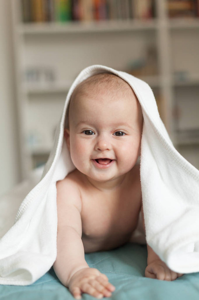 Küçük bebek gülümsüyor, gülüyor. Beyaz havlunun üzerinde tatlı bir bebek yatıyor.. - Fotoğraf, Görsel