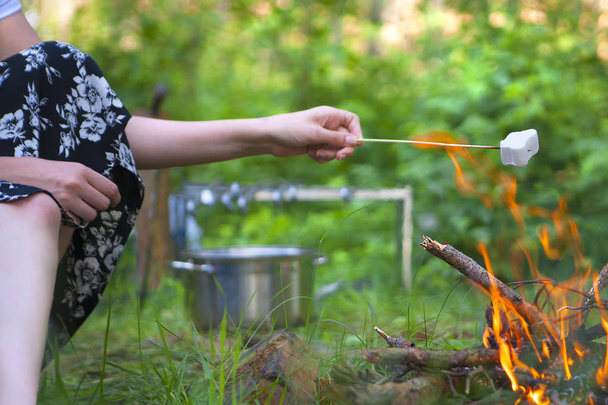 Žena peče marshmallows nad táborákem. Opékané marshmallows otevřít plamen na špejli - Fotografie, Obrázek