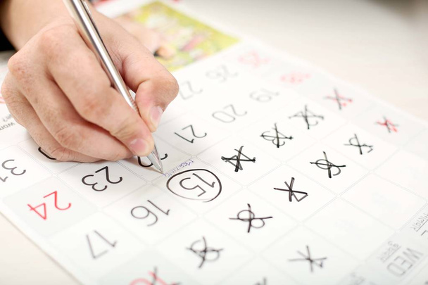 Mann markiert mit Stift 15 Termine im Kalender. - Foto, Bild