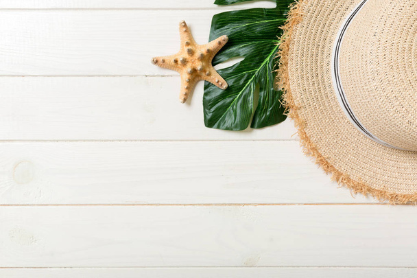 Sombrero de paja, hoja verde y estrella de mar Sobre un fondo de madera blanca. arriba ver concepto de vacaciones de verano con espacio de copia
 - Foto, Imagen