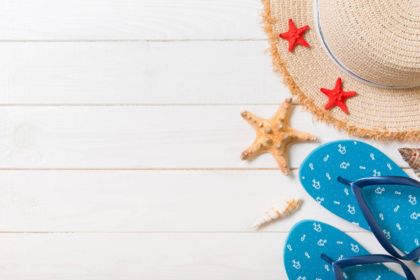 Sombrero de paja, chanclas azules y estrellas de mar sobre un fondo de madera blanca. arriba ver concepto de vacaciones de verano con espacio de copia
 - Foto, imagen