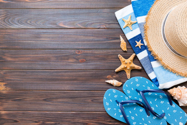Sombrero de paja, chanclas azules, toalla y estrella de mar Sobre un fondo de madera oscura. arriba ver concepto de vacaciones de verano con espacio de copia
 - Foto, imagen