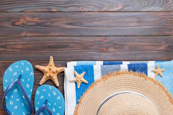 Olkihattu, siniset sandaalit, pyyhe ja meritähti tummalla puupohjalla. top view kesäloma käsite kopioi tilaa
 - Valokuva, kuva