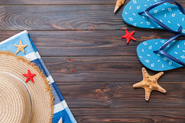 Sombrero de paja, chanclas azules, toalla y estrella de mar Sobre un fondo de madera oscura. arriba ver concepto de vacaciones de verano con espacio de copia
 - Foto, imagen
