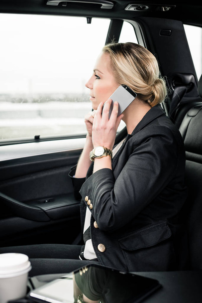 Businesswoman using smartphone in the car - Photo, image
