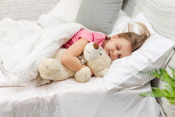 niedliches kleines Mädchen schläft mit Teddybär - Foto, Bild