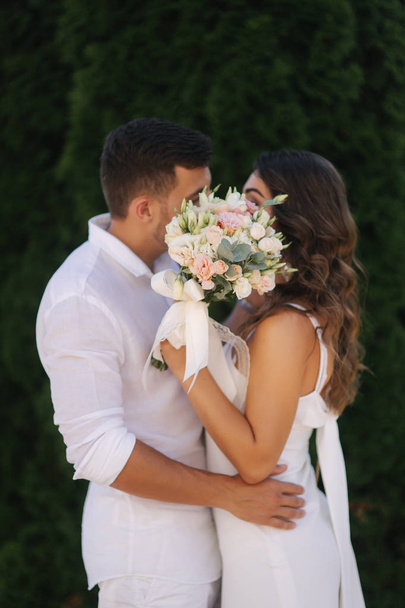 Man kiss woman and hide by bouquet. Wedding day - Foto, Imagen