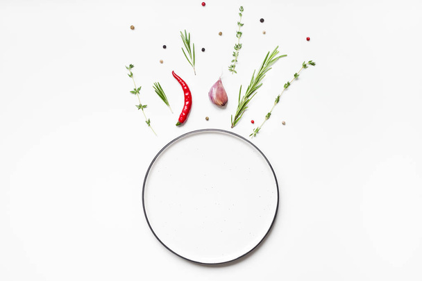 Пустая тарелка с зелеными травами и специями вокруг
 - Фото, изображение