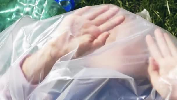 Imágenes conceptuales de contaminación plástica. Mujer acostada dentro de una bolsa de plástico
. - Imágenes, Vídeo