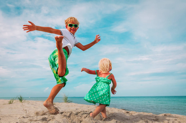 cute boy and girl dance at beach, kids enjoy vacation at sea - Foto, afbeelding