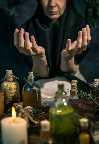 Dunkle Hexe bei der Arbeit: Schwarze Magierin macht die Hexe, indem sie Kräuter mischt, Zaubersprüche ausspricht und magische Rituale ausführt - Foto, Bild