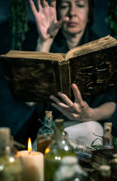 Dunkle Hexe bei der Arbeit: Schwarze Magierin macht die Hexe, indem sie Kräuter mischt, Zaubersprüche ausspricht und magische Rituale ausführt - Foto, Bild