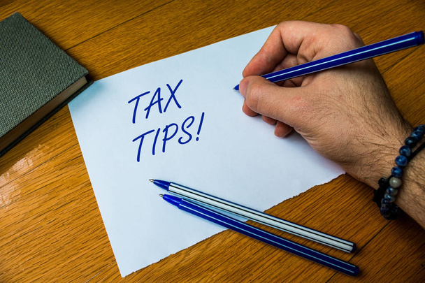 Handwriting text writing Tax Tips. Concept meaning compulsory contribution to state revenue levied by government Top vie male handwriting wooden desk electronic device Writing down project. - Photo, Image