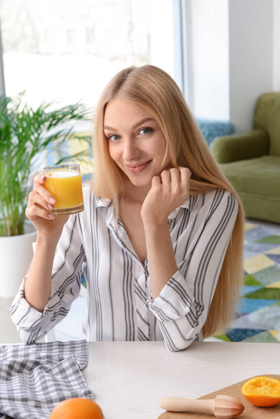 mooie jonge vrouw drinken vers sap thuis - Foto, afbeelding