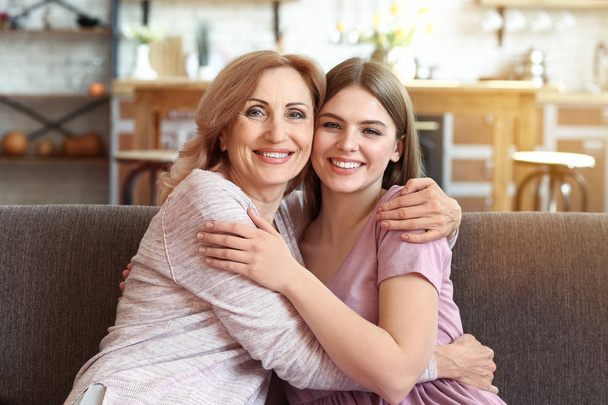 Happy mother and daughter sitting on sofa at home - Fotografie, Obrázek