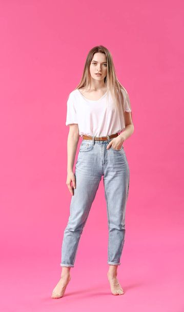 stilvolle junge Frau in Jeans auf farbigem Hintergrund - Foto, Bild