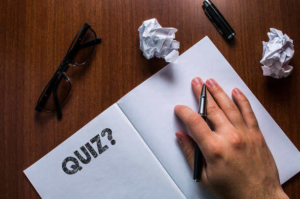 Writing note showing Quiz Question. Business photo showcasing test of knowledge as competition between individuals or teams Man hand resting pen open notebook reading glasses lying wooden table. - Photo, Image