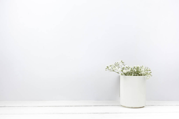 Gri beton bir duvarın arkasında çiçek vazosu olan ahşap bir masa. - Fotoğraf, Görsel
