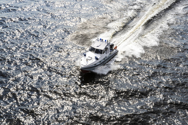 white boat coastal rescue rushes on the waves of the Baltic sea, beautiful glare on the water and water stains from the boat - Photo, image