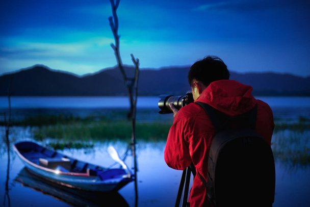 Photographe de voyage prenant une photo avec la nature le lac au coucher du soleil à la vie nocturne avec appareil photo sur trépied, Concentrer l'attention sur la nature vue sur la montagne et le lac, Photographie naturelle concept relaxant
. - Photo, image