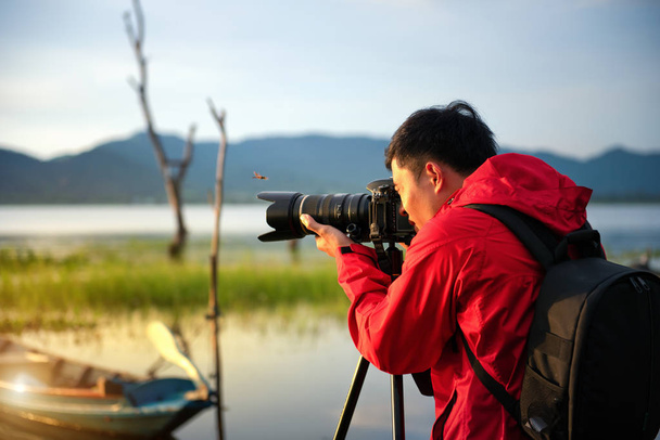 Photographe de voyage prenant une photo avec la nature le lac au coucher du soleil avec appareil photo sur trépied, Concentrer l'attention sur la nature vue sur la montagne et le lac, Photographie naturelle concept relaxant
. - Photo, image