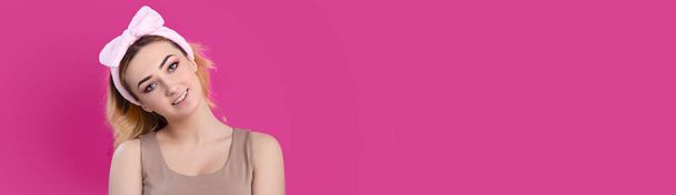 portrait of a beautiful girl woman in a headband for make up on pink studio background, concept of beauty, advertising cosmetics, body care - 写真・画像