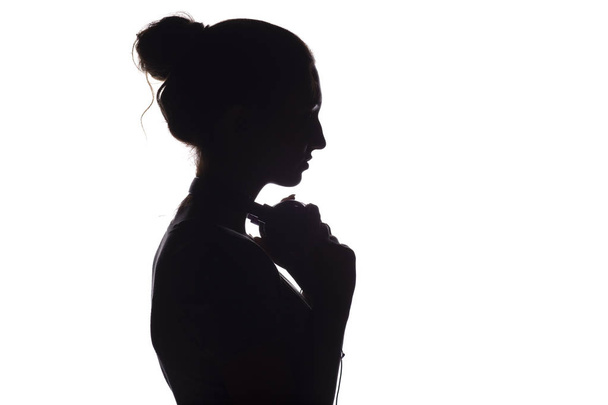 Silhueta de uma menina com fones de ouvido ao redor do pescoço, uma jovem mulher ouvindo música em um fundo branco isolado, conceito de hobby e relaxamento
 - Foto, Imagem