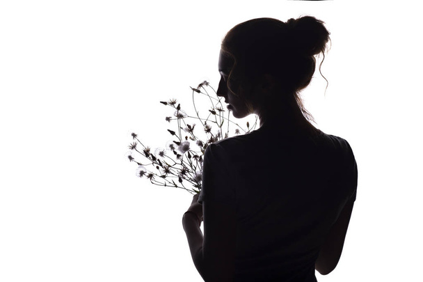 silhouette profile of a beautiful girl with a bouquet of dried flowers on a white isolated background - Foto, imagen