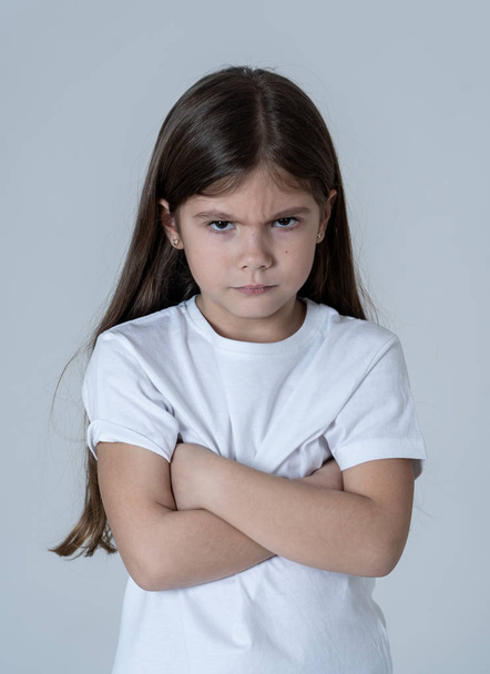 Portrait of a cute pretty child girl looking angry and disappointed with her arms crossed. Isolated on neutral background. In children feelings and behaviour and human emotions and expressions. - Photo, image