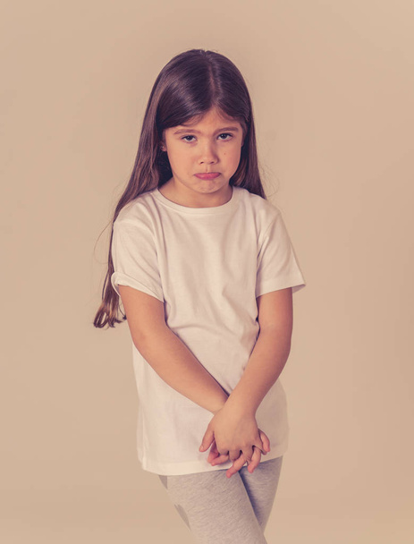 Portrait of a pretty young child looking unhappy and sad making funny cute facial expressions. Isolated on neutral background. Human emotions and children behaviour and feelings. - 写真・画像