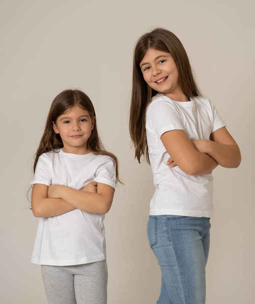 Cute portrait of two cheerful siblings girls sisters having fun together hugging and laughing posing for the camera. Studio shot with copy space. In Family and children happy moments together. - Photo, image