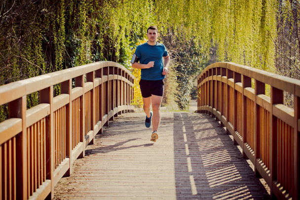 Bir köprü eğitimi üzerinde bir şehir parkında çalışan erkek koşucu - Fotoğraf, Görsel