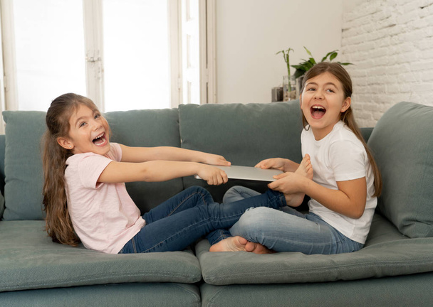 Younger and older girls fighting for laptop arguing over playing on the internet. Lifestyle portrait of sisters not sharing computer in Relationship between siblings and technology addiction concept. - Φωτογραφία, εικόνα