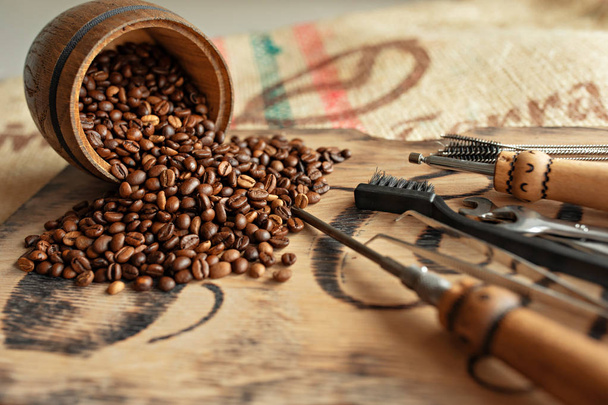 Gereedschappen voor het repareren van koffiemachines close-up. Koffiebonen, houten plank, koffiezetapparaat, keuken tafel - Foto, afbeelding