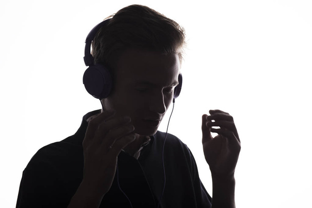 profil visage silhouette de mélomane adolescent écoute chanson préférée dans les écouteurs, beau jeune homme sur fond blanc isolé, concept mode de vie des jeunes, passe-temps
 - Photo, image