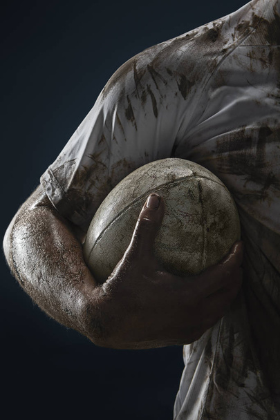 Rugby-Spieler Hände mit Ball auf dunklem Hintergrund. Nahaufnahme - Foto, Bild